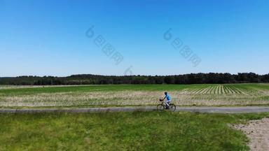 空中认不出来男人。速度单小道穿越大草地绿色电自行车运动男性旅游享受一天下坡骑自行车风景优美的农村